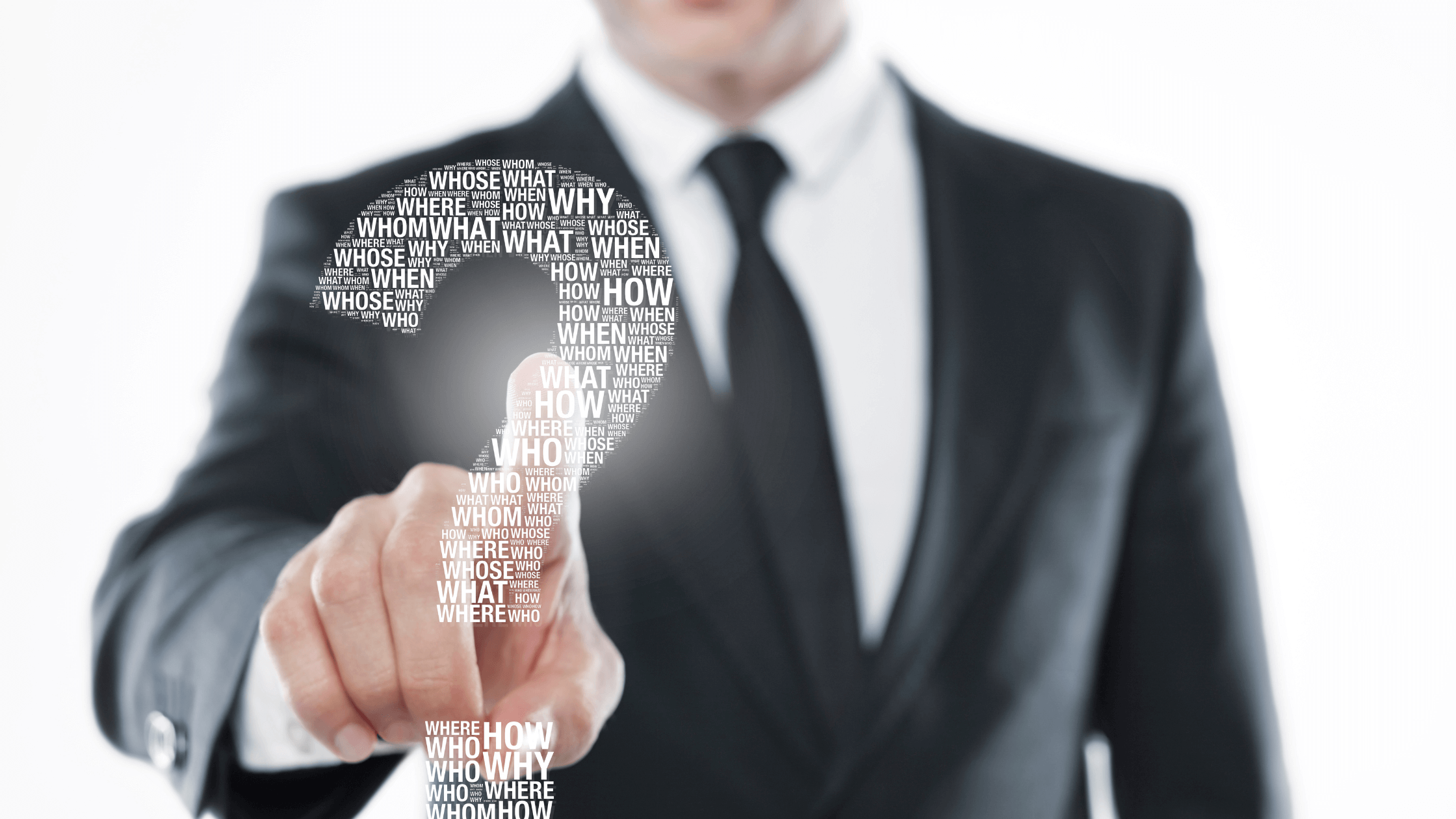 Businessman in a suit pointing at a digital question mark filled with words like what, why, who, and how.