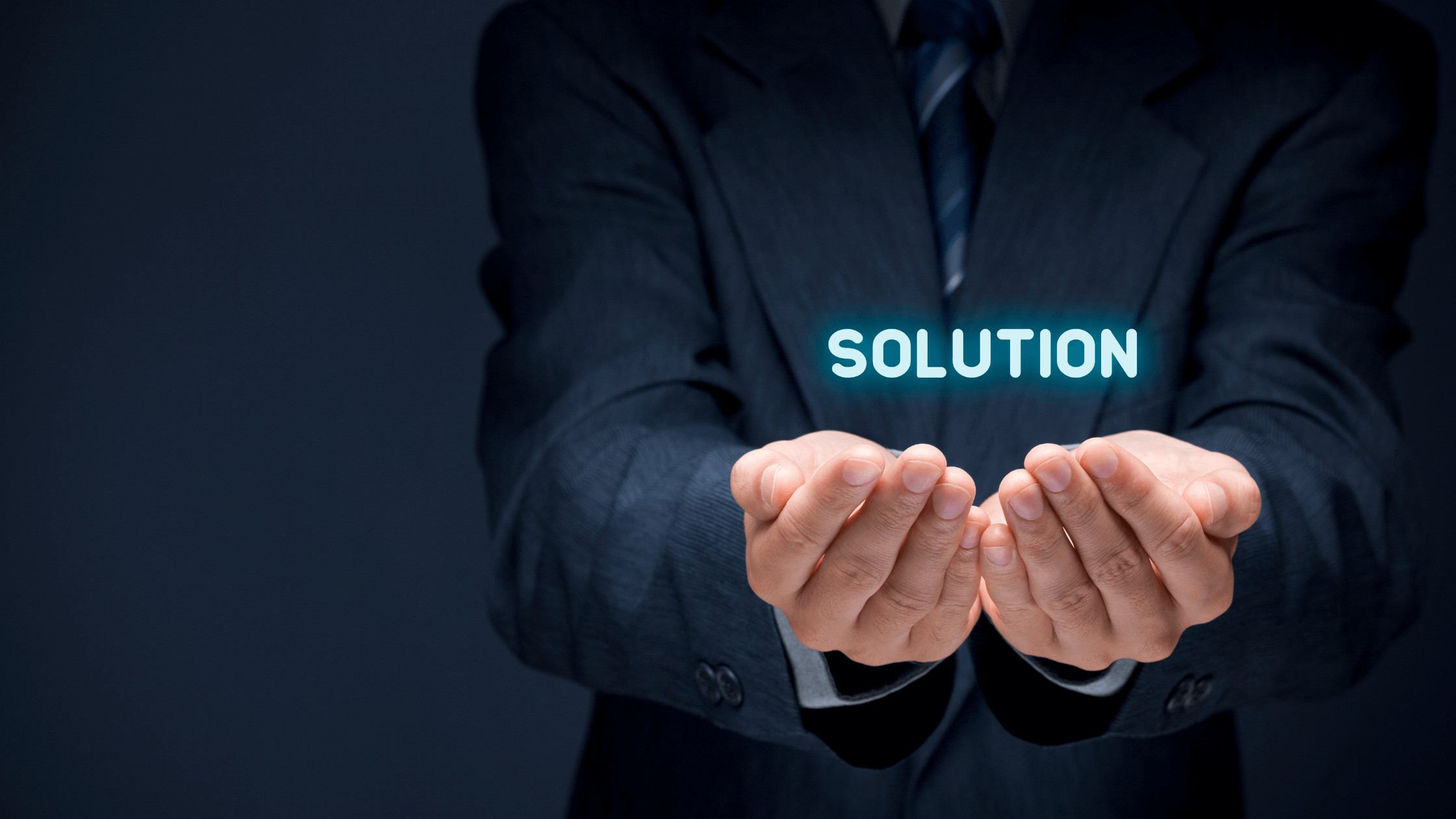 Businessman in a suit holding glowing text that reads 'solution' in his hands.