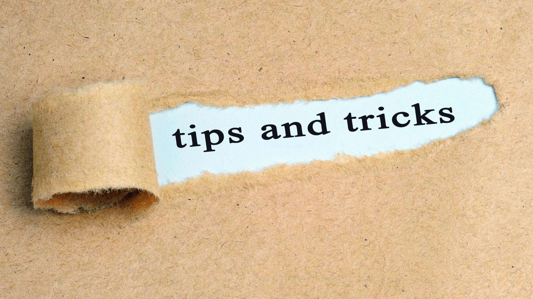Text “tips and tricks” revealed through torn brown paper background.