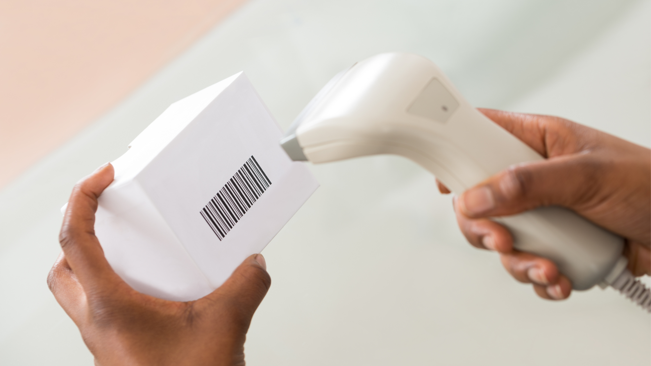 Close-up of hands scanning a barcode on a product box using a barcode scanner, representing POS with barcode scanner integration.