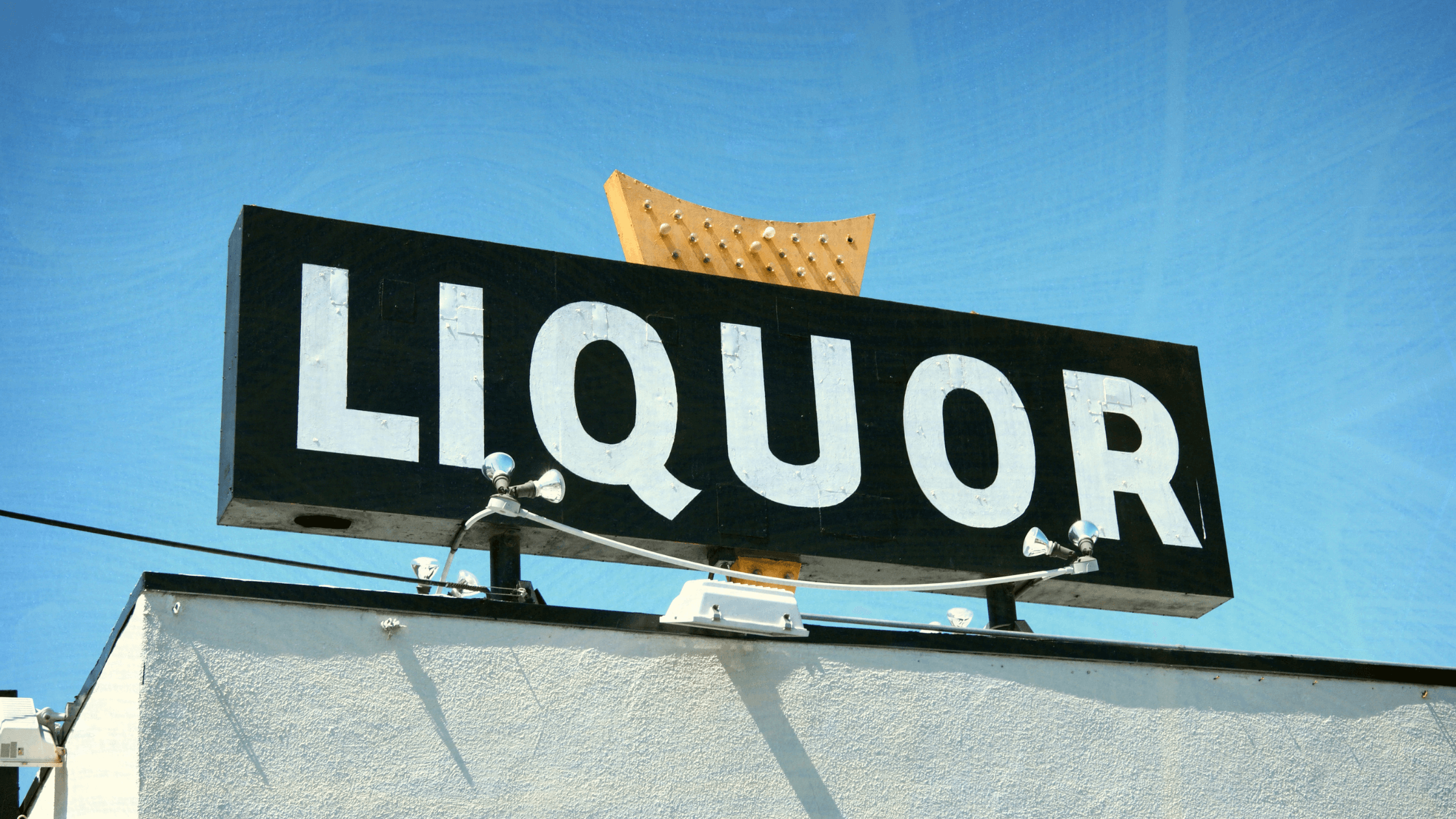 Outdoor liquor store sign against a bright blue sky.
